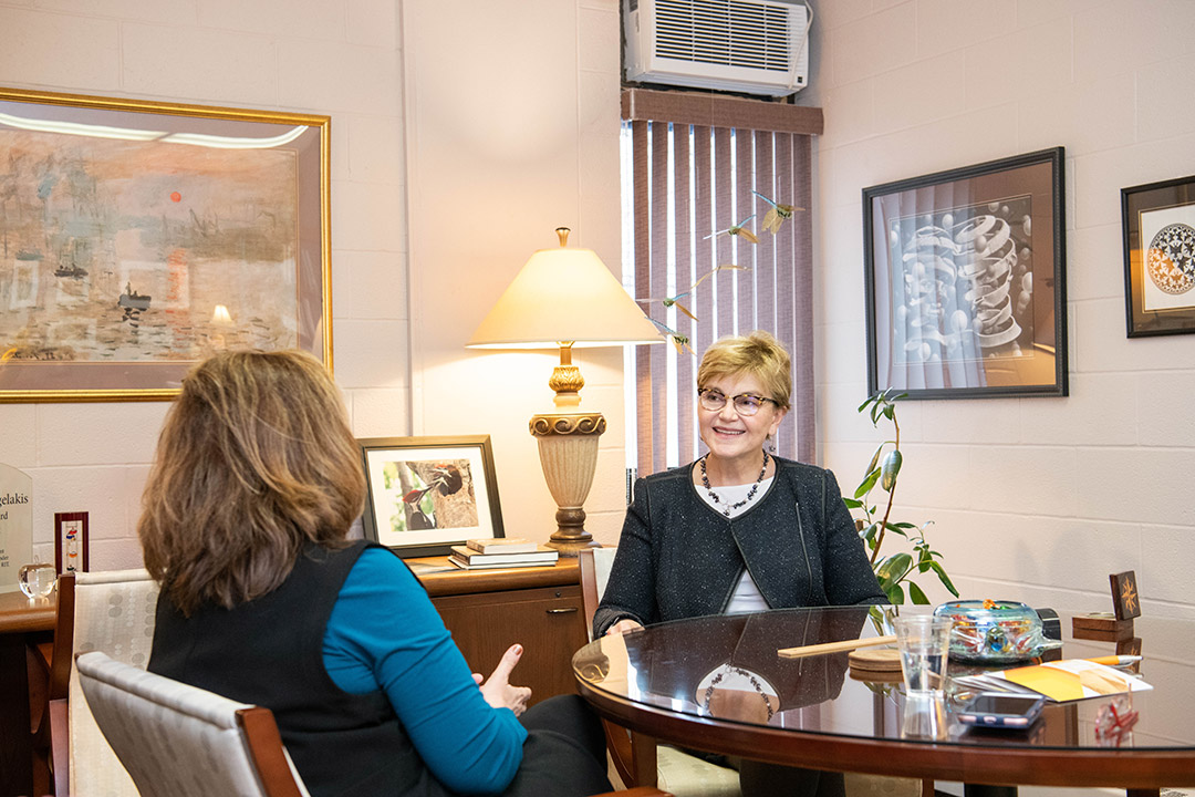 two women talking in a dean's office.
