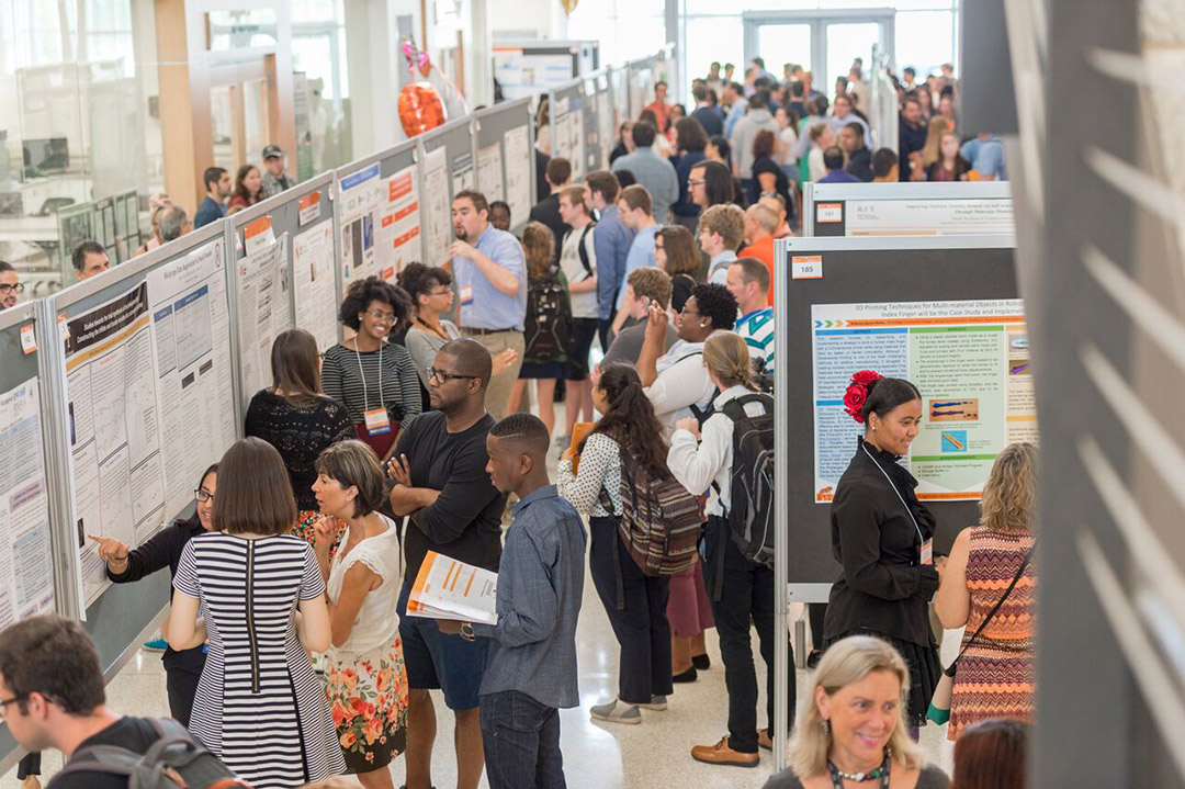 crowd of people looking at poster presentations.