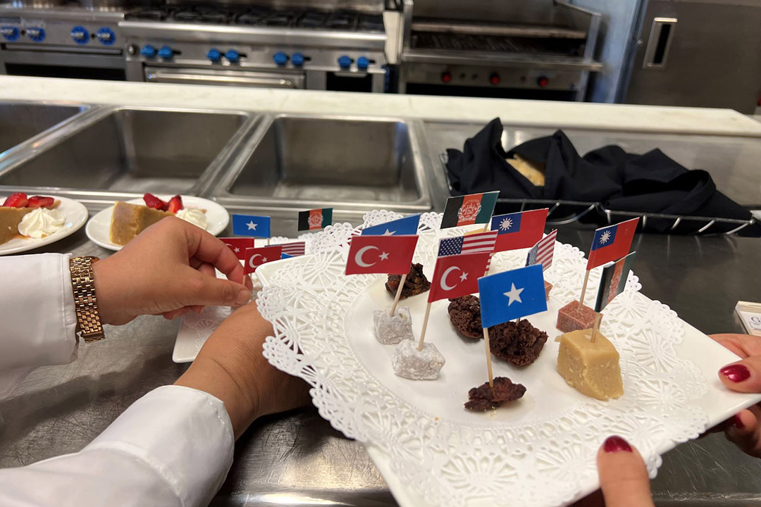 a plate with samples of foods stuck with flags from different countries.