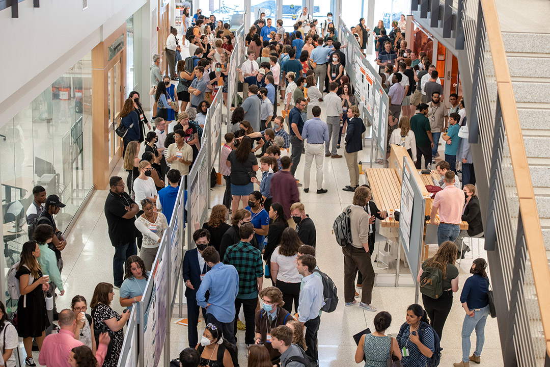 crowd of people looking at research posters in an atrium.