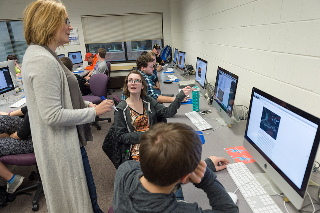 professor talking to students in a computer lab.