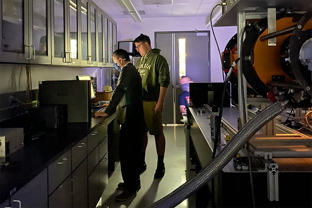 Student and professor in lab, looking at computer screen