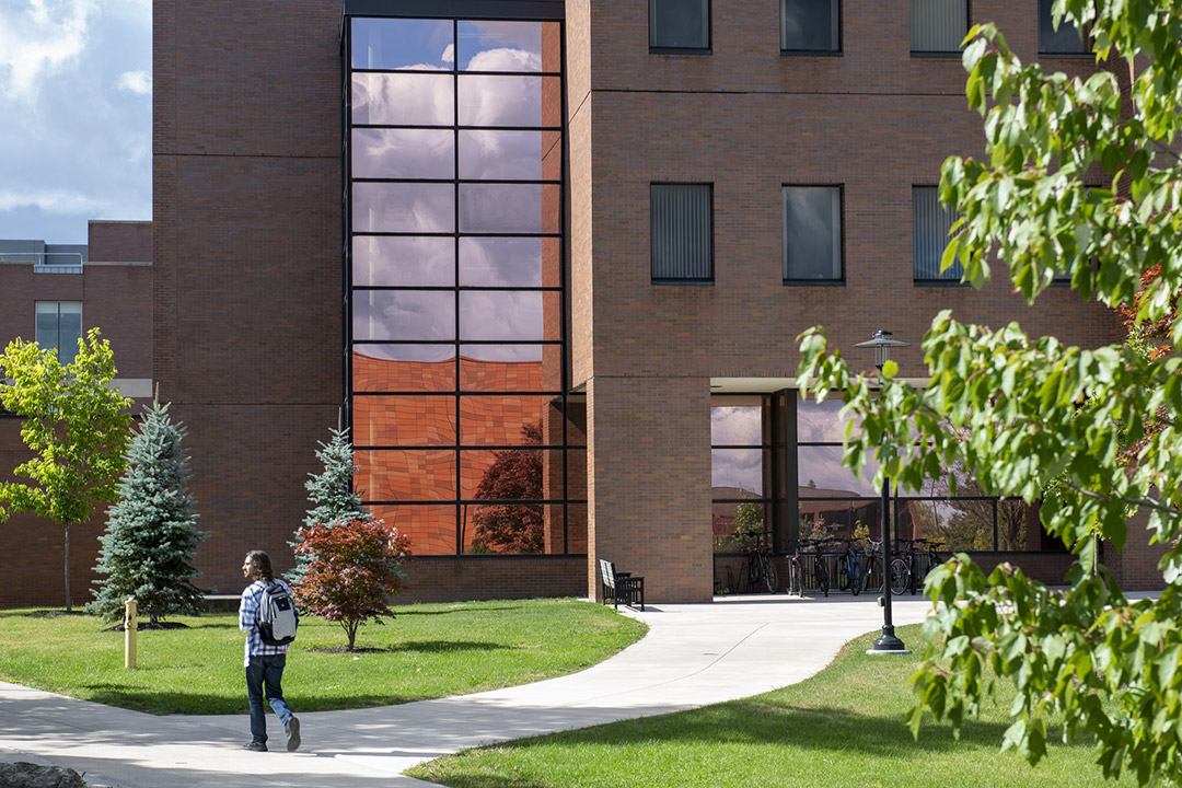 person walking outside near a brick and glass building.