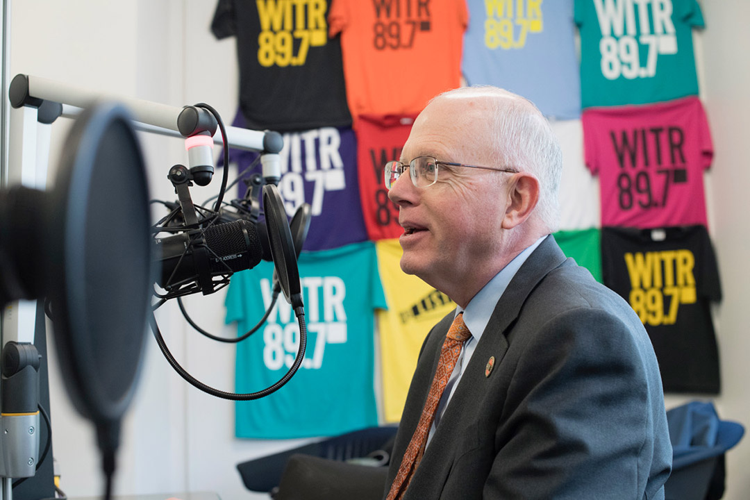 RIT president David Munson talking into a radio station microphone.