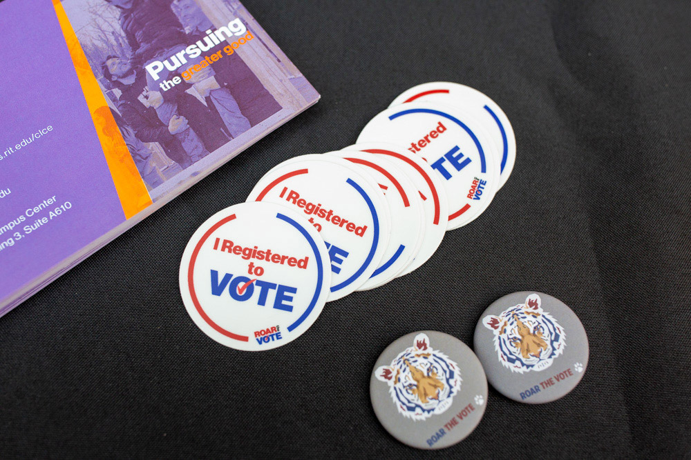 table with Roar the Vote buttons and I registered to vote stickers.