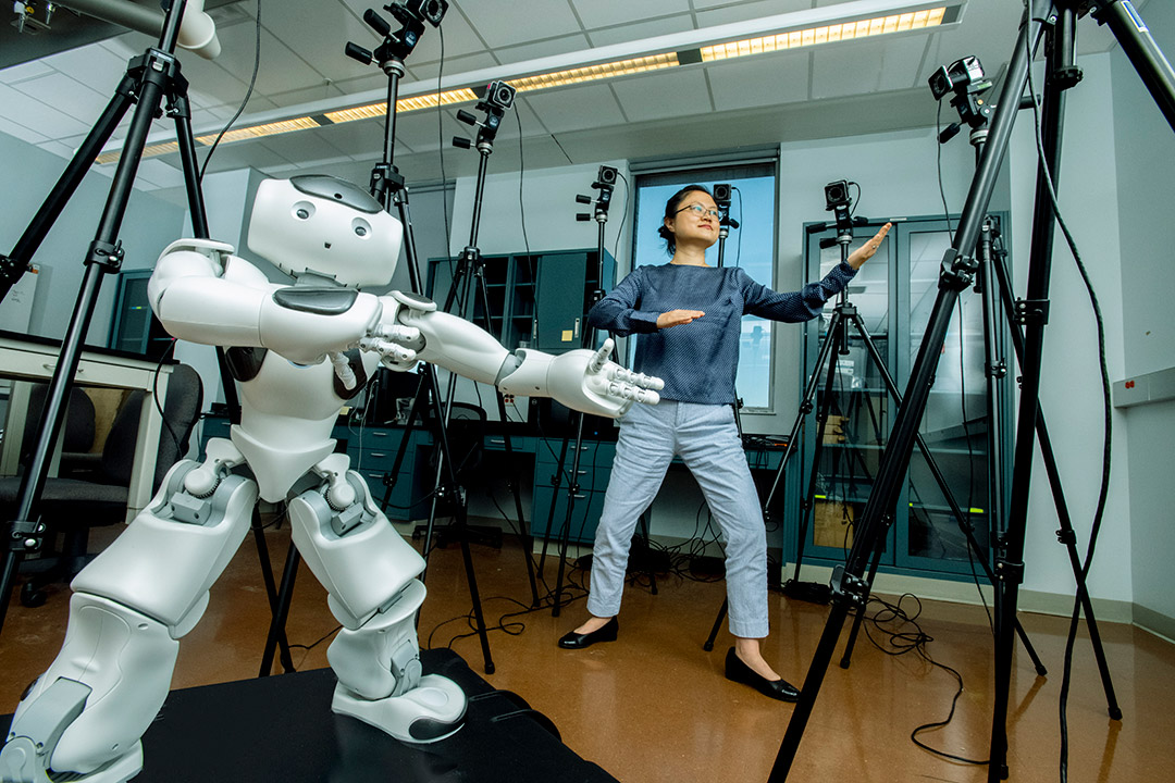 person doing Tai Chi with a small humanoid robot.