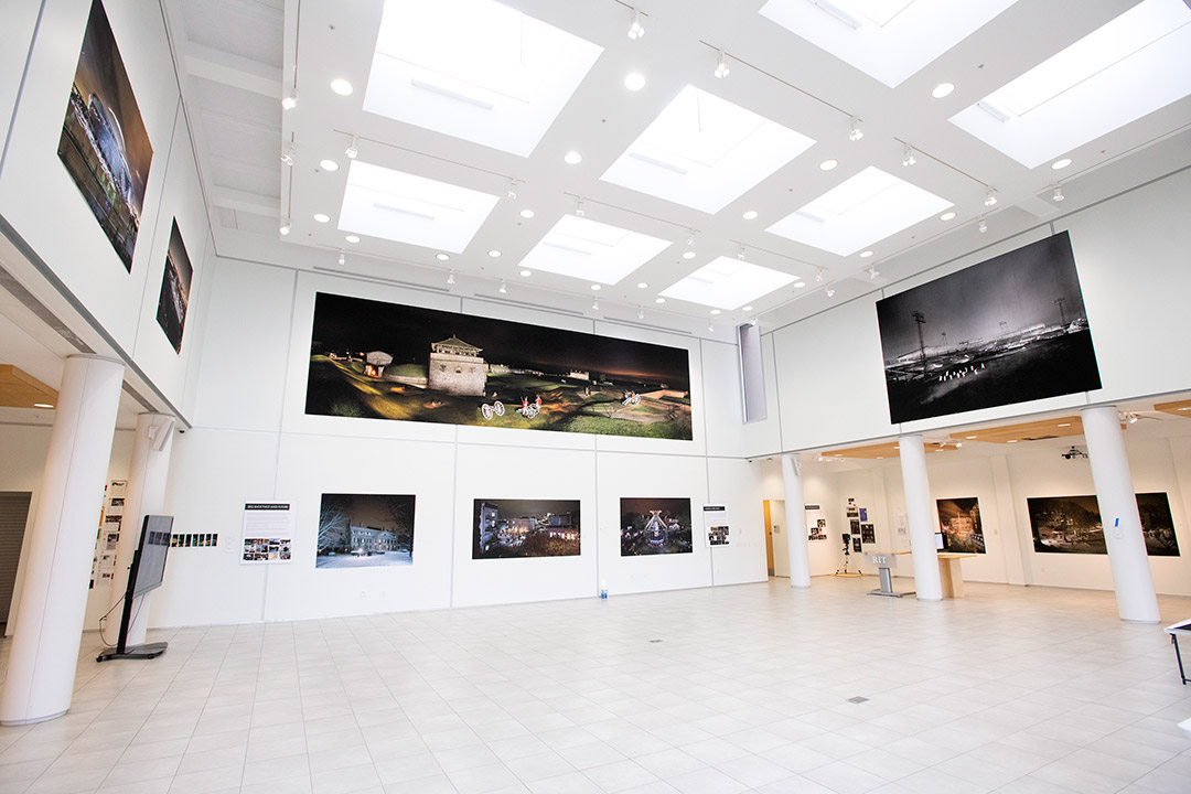 an art gallery with photos of places and landmarks on all of the walls.