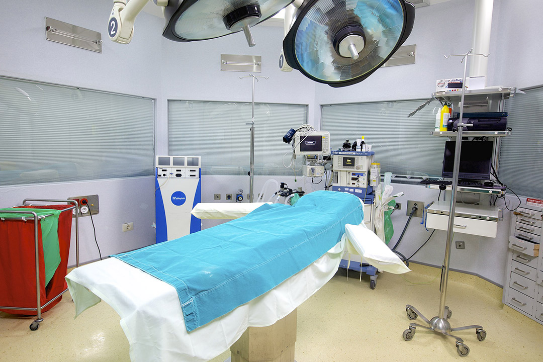 an operating room with a bed, lights, and monitors.