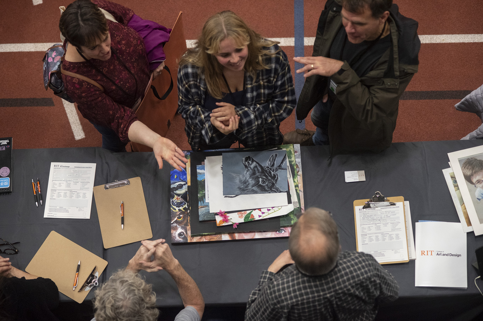 An overhead view of a student getting their portfolio reviewed by RIT faculty.