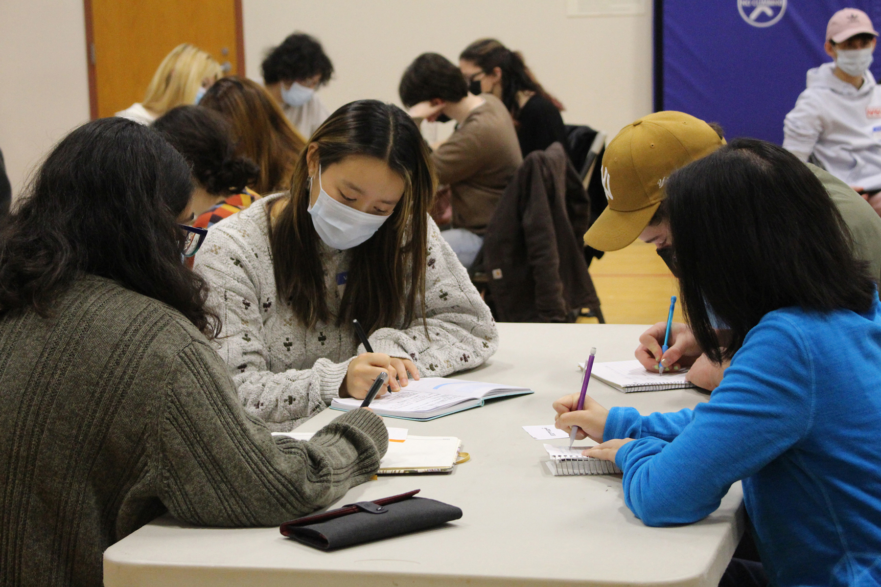 A group of students write in notepads.