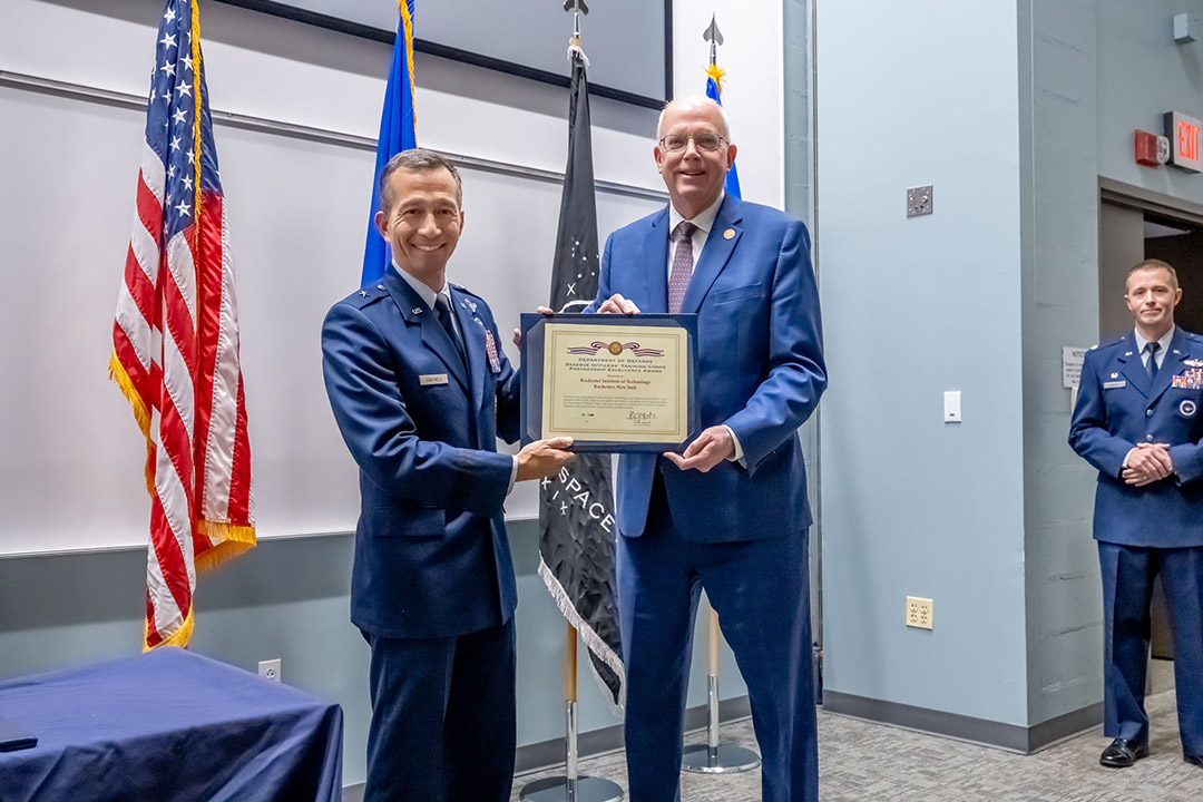 Air Force office and RIT president holding a certificate and posing for a photo.