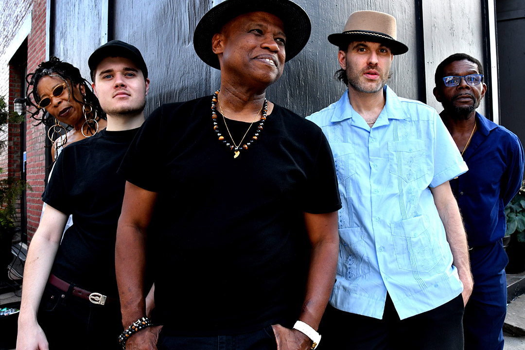 five members of a poetry band posing at the corner of a building.