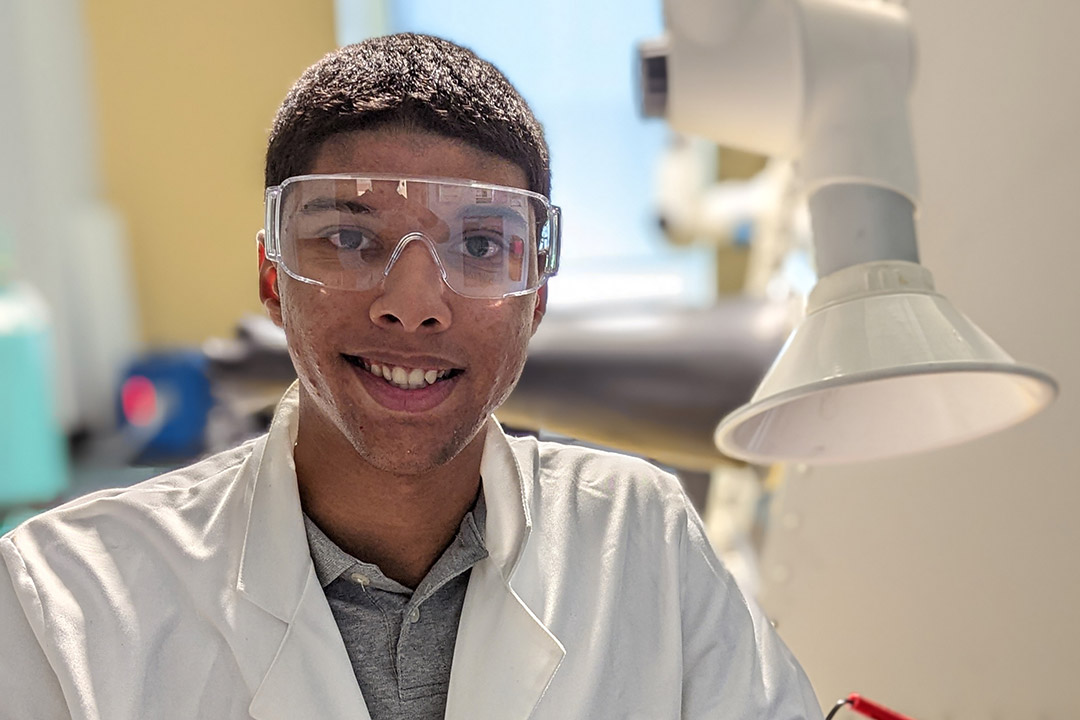 student wearing a lab coat and protective glasses.