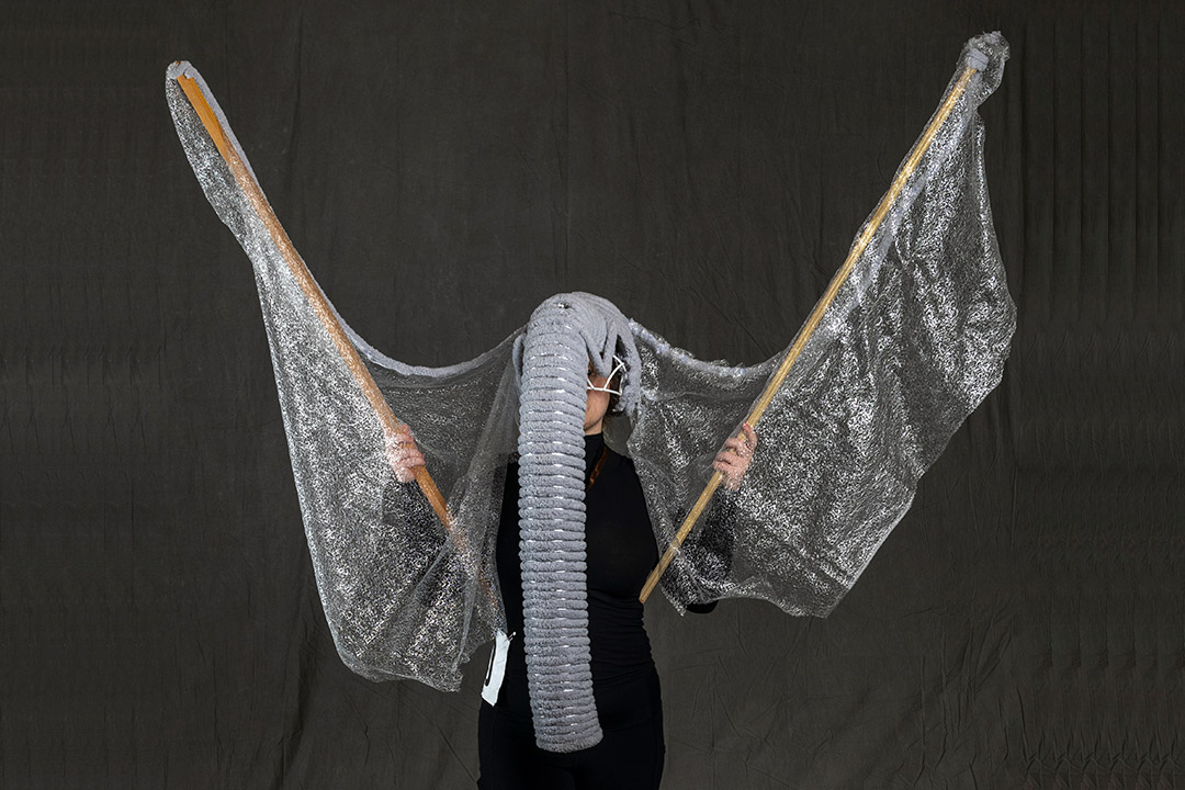 student showcasing wearable sculpture that looks like an elephant trunk and ears.