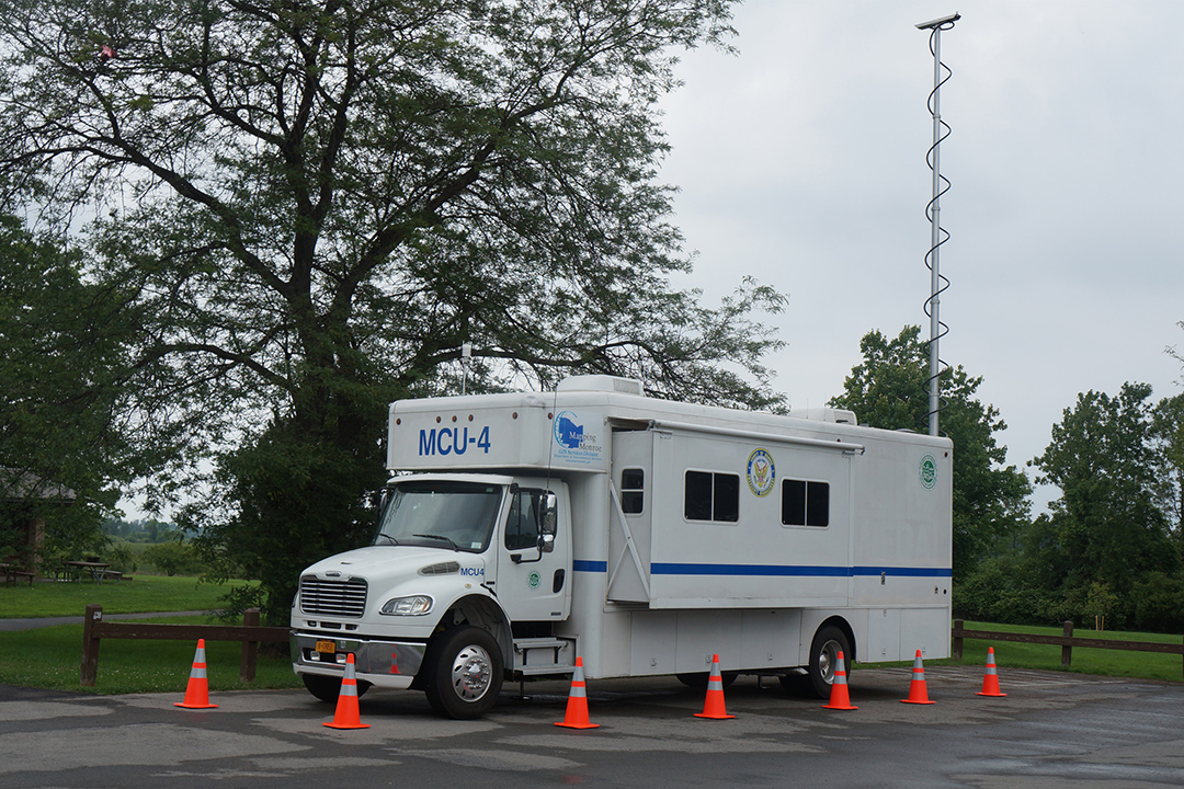 a camper-looking truck with a large antenna attached to the back.