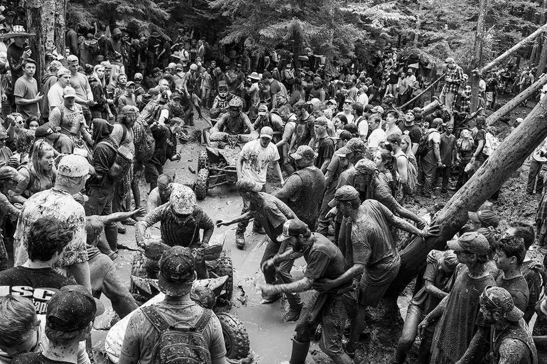 black and white photo of a crowd of muddy spectators along an ATV race track.