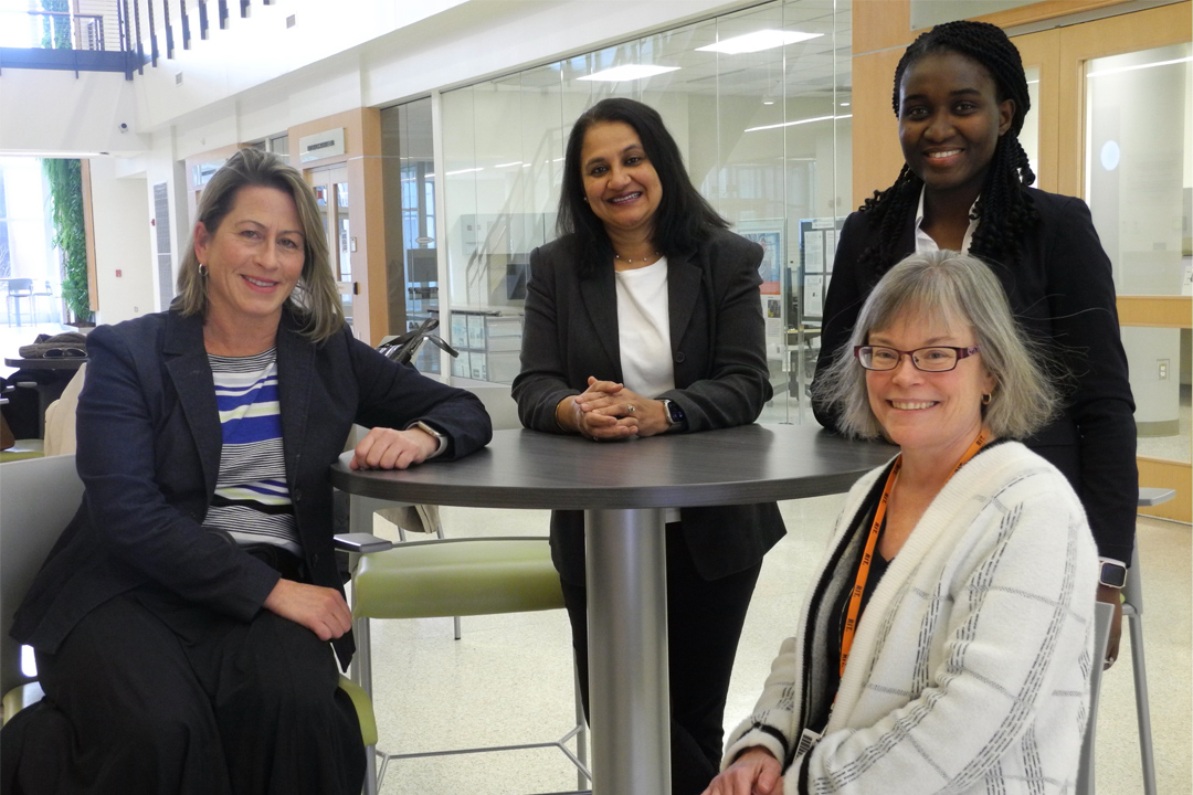 Four women sitting around a table and smiling.