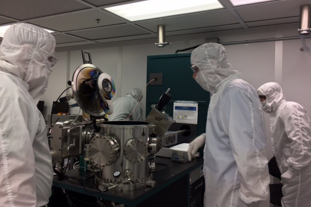 researchers wearing clean suits in a lab.