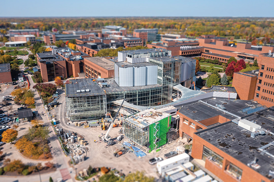 aerial view of a building under construction in the midst of brick buildings.