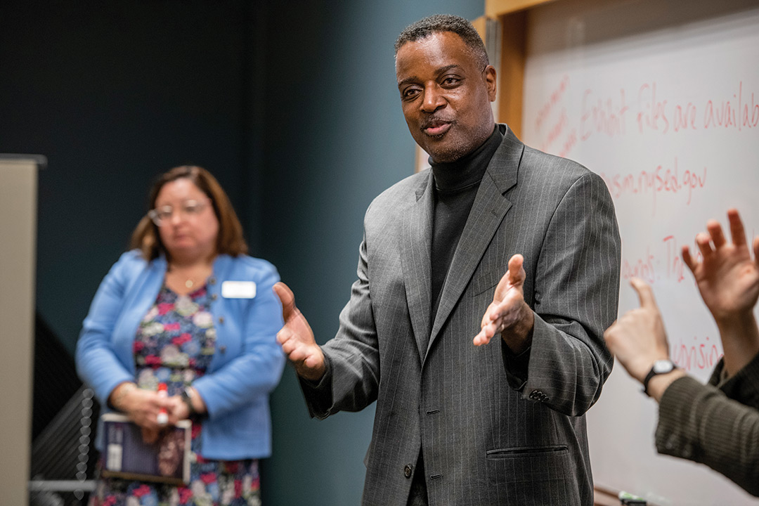 man presenting at the front of a room.