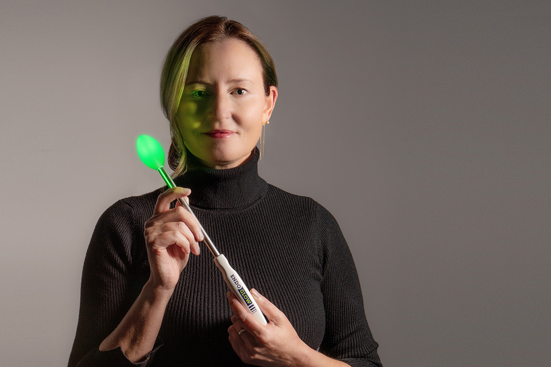 woman holding a medical wand with a glowing green bulb on the end.