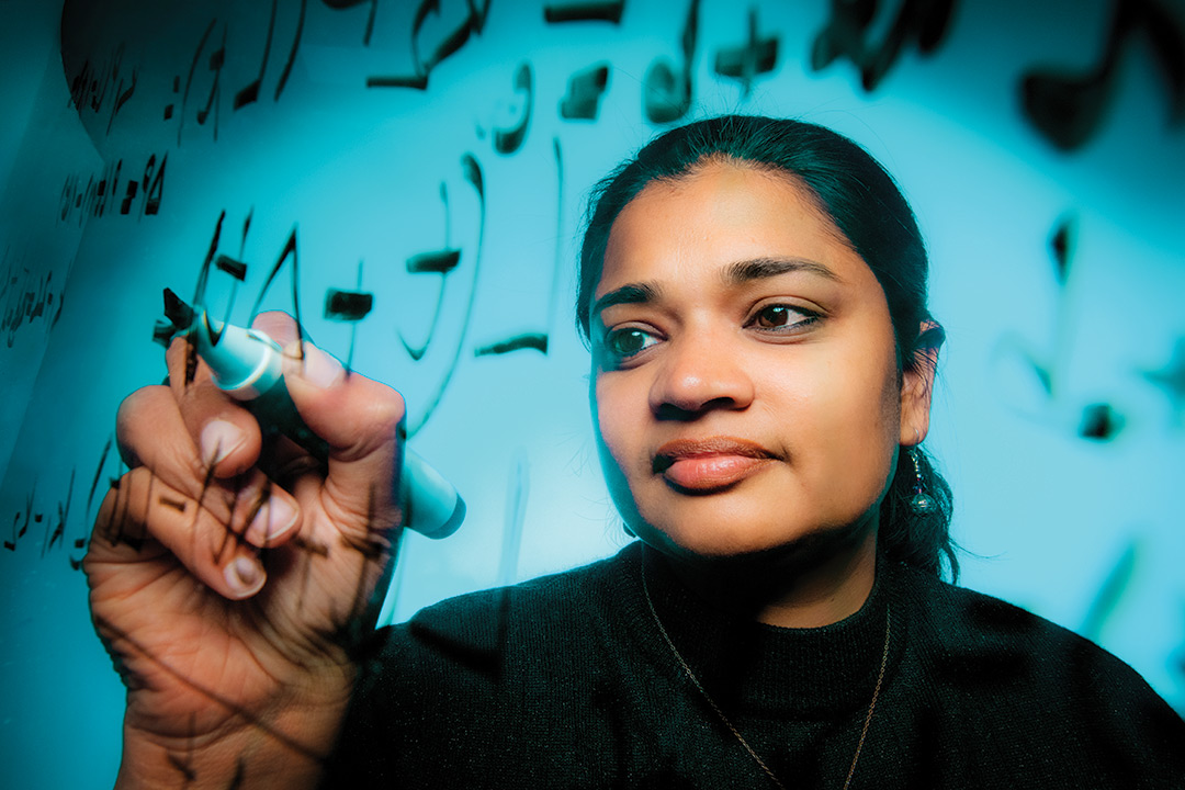 researcher writes on a clear surface with a marker.