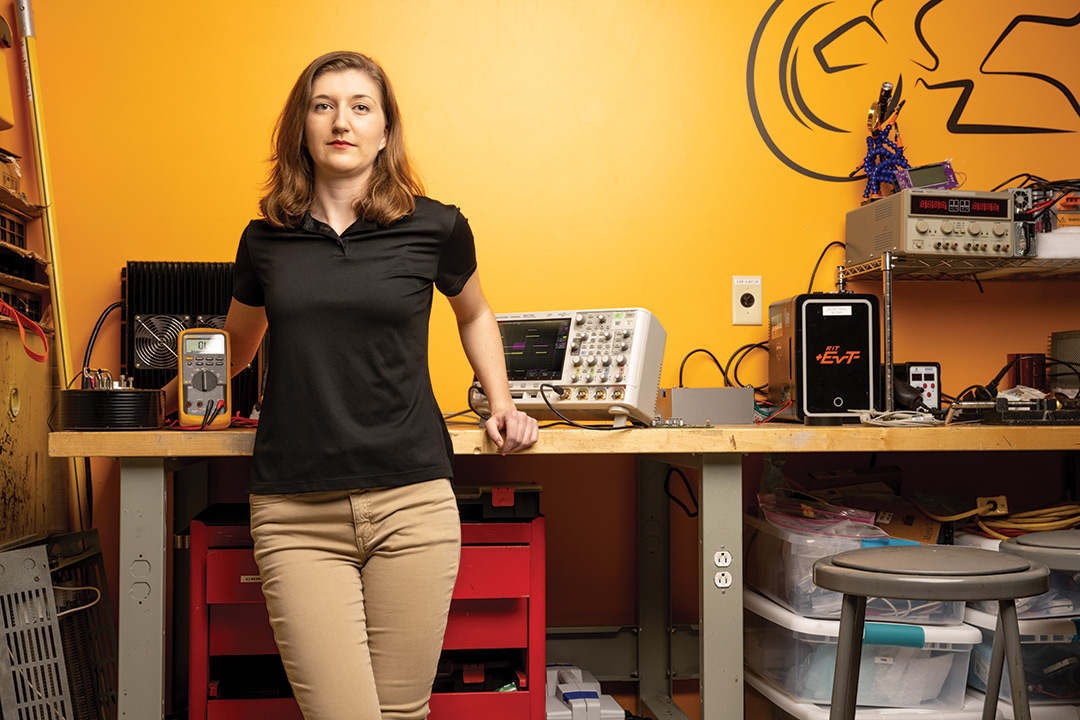 college student posing in front of workbench with measuring tools.