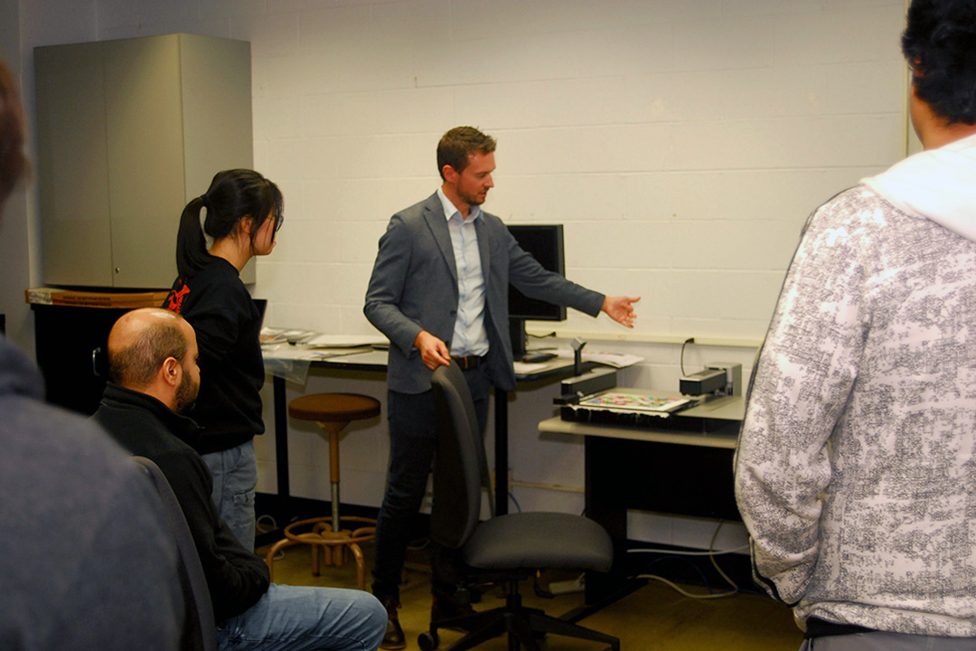 Man demonstrates an instrument to students in a classroom.