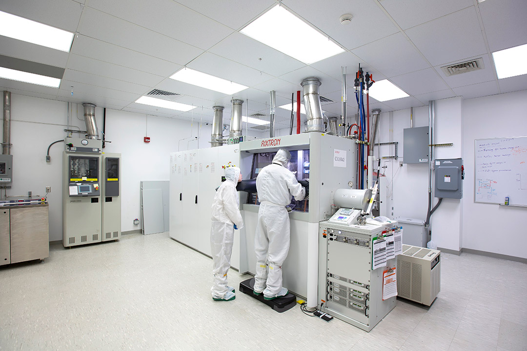 two people wearing clean suits working with engineering equipment.