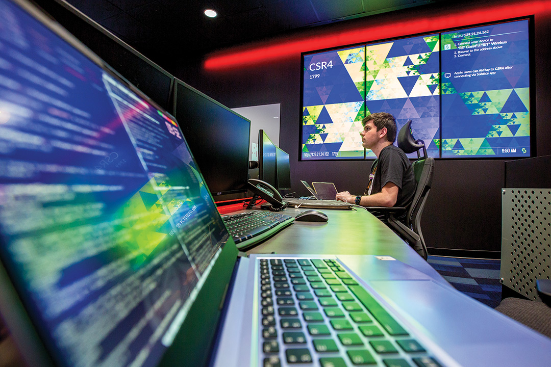 college student working on a computer in a cybersecurity lab.