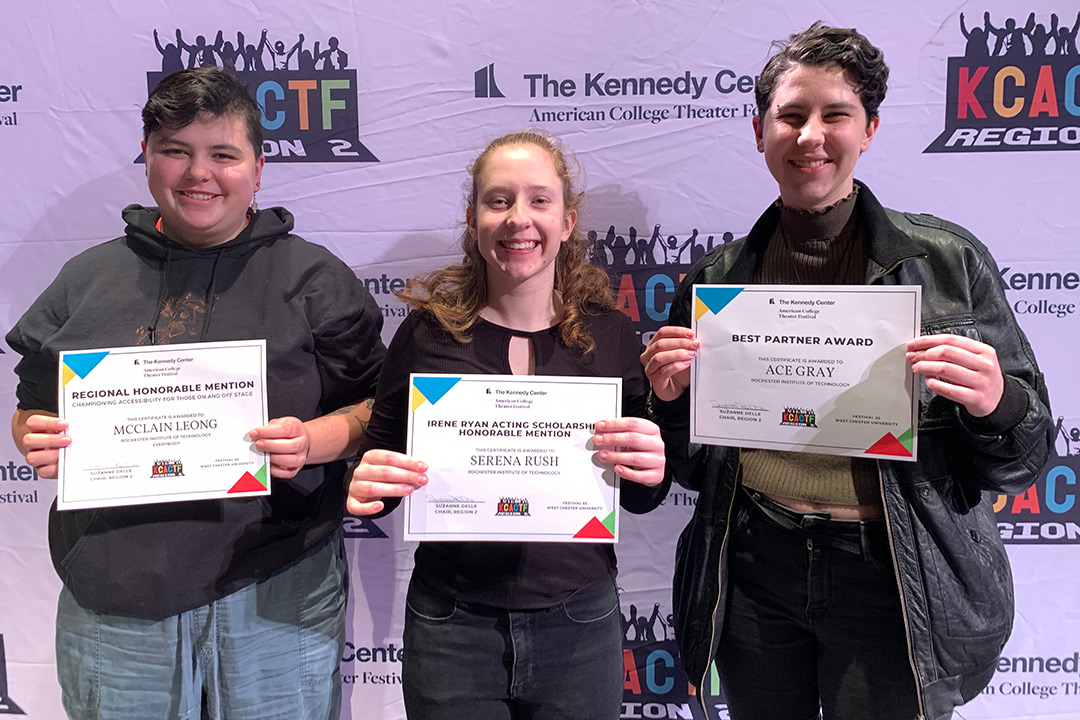 three college students holding award certificates.