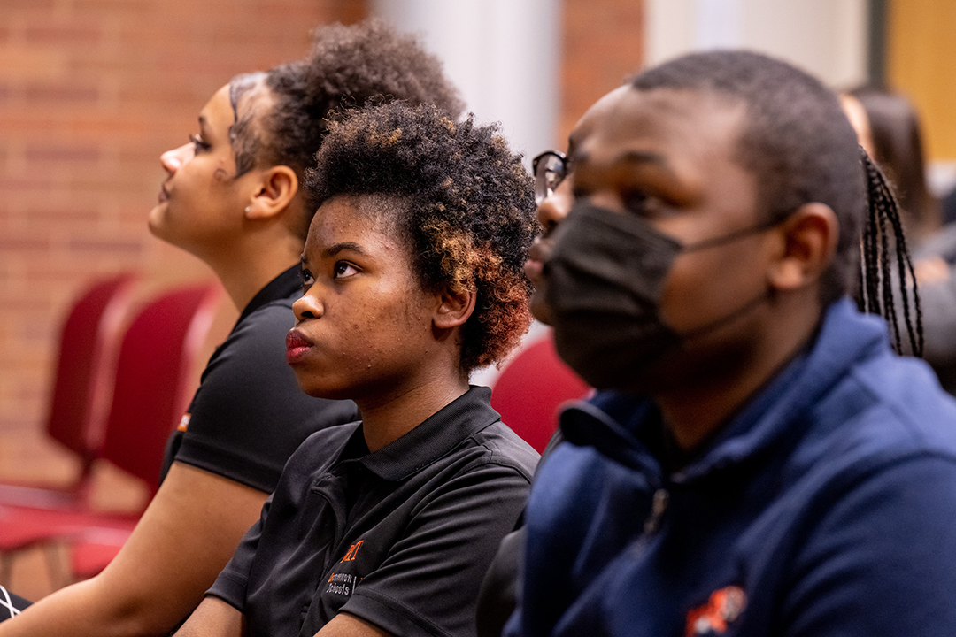 Up close photo of students sitting in chairs looking ahead.