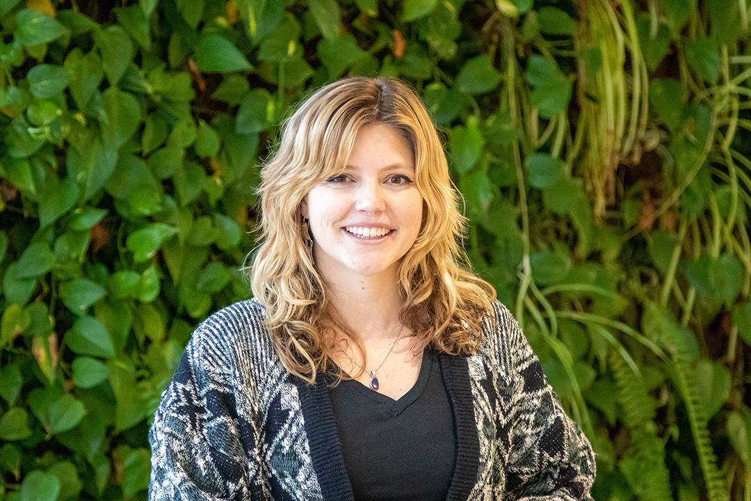 woman standing in front of a plant wall.