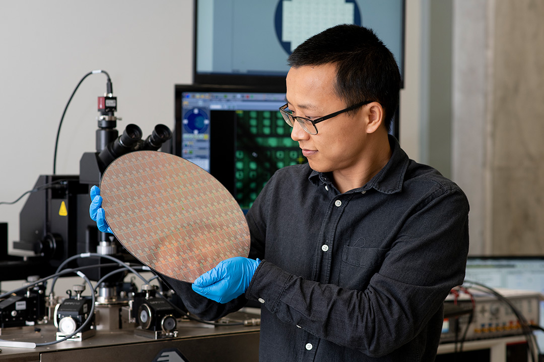 researcher holding a large, round semiconductor chip.