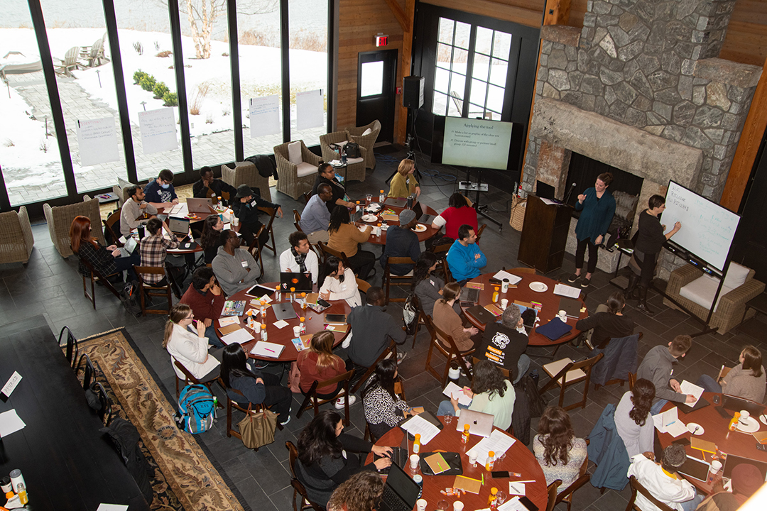 Over head picture of graduate school workshop. Students at tables with work supplies.