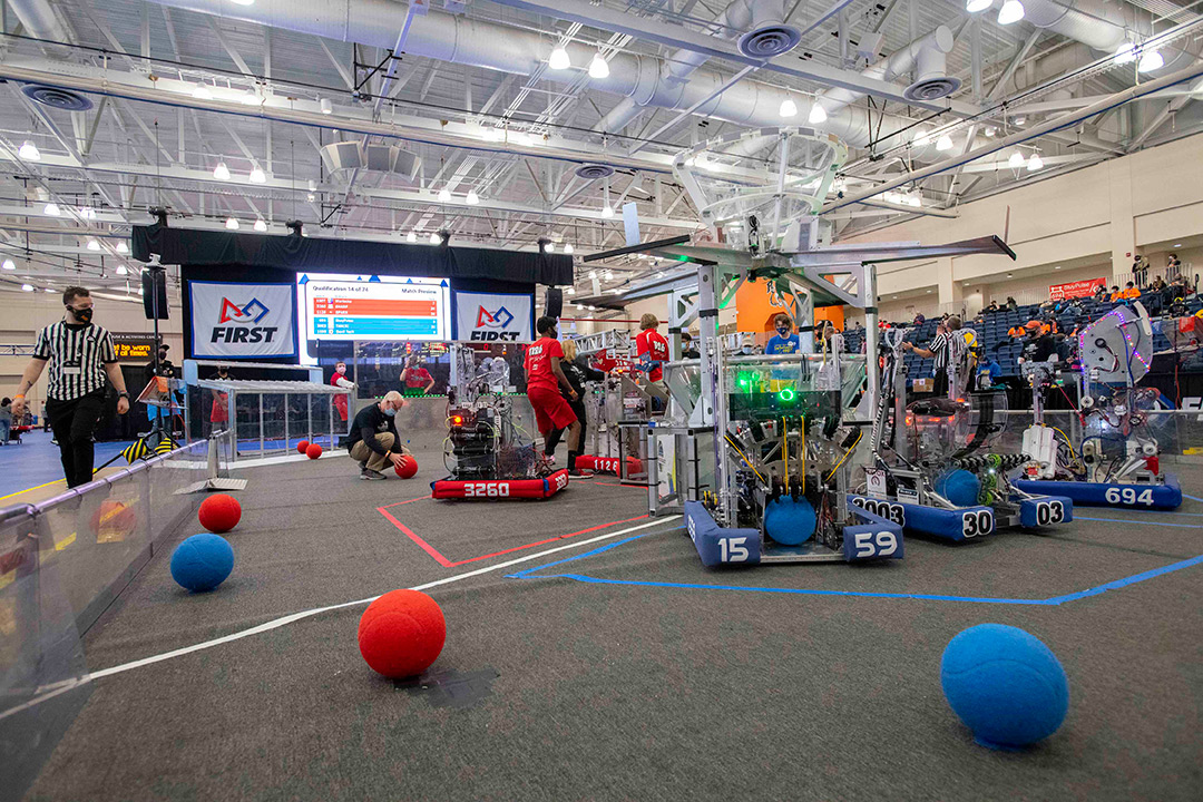student built robots in a playing field picking up blue and red balls.