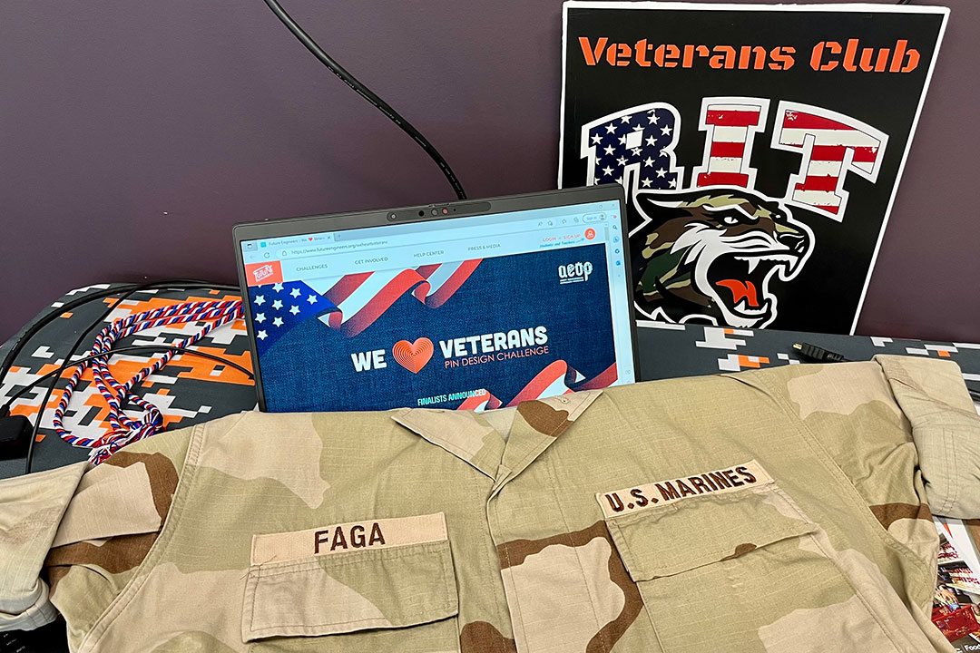 U.S Marine blouse draped over a computer with We Heart Veterans and the RIT Veterans Club sign