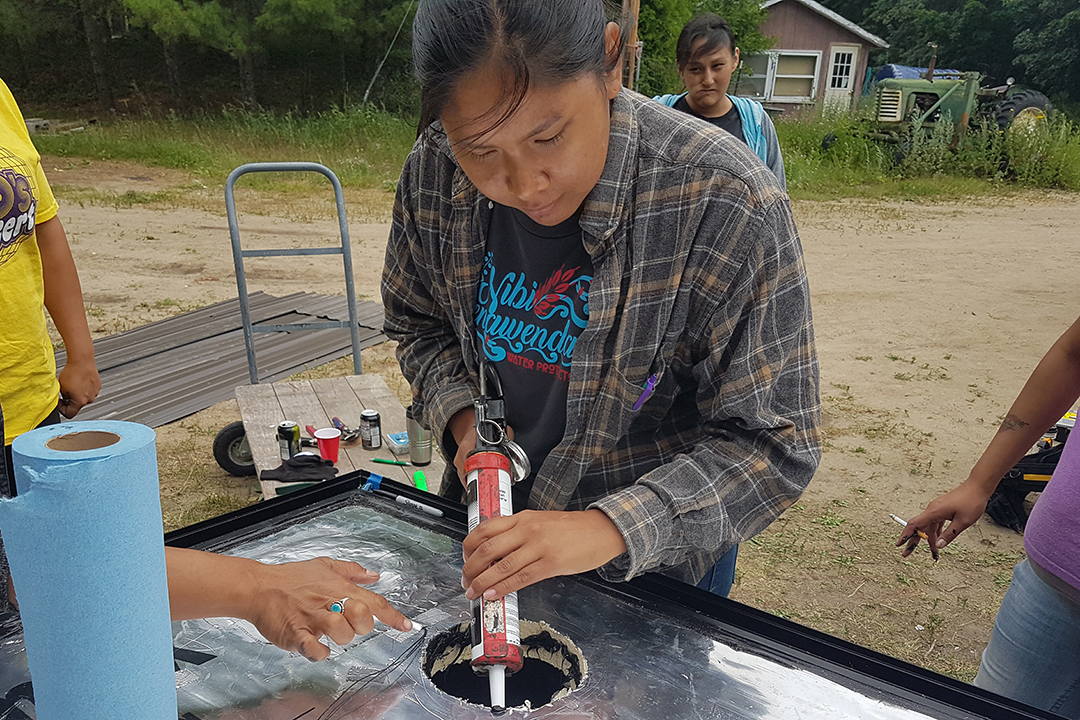 Person works on a solar panel furnace outdoors.