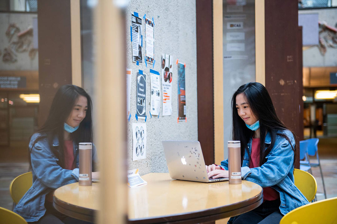 student working on a laptop sitting at a table.