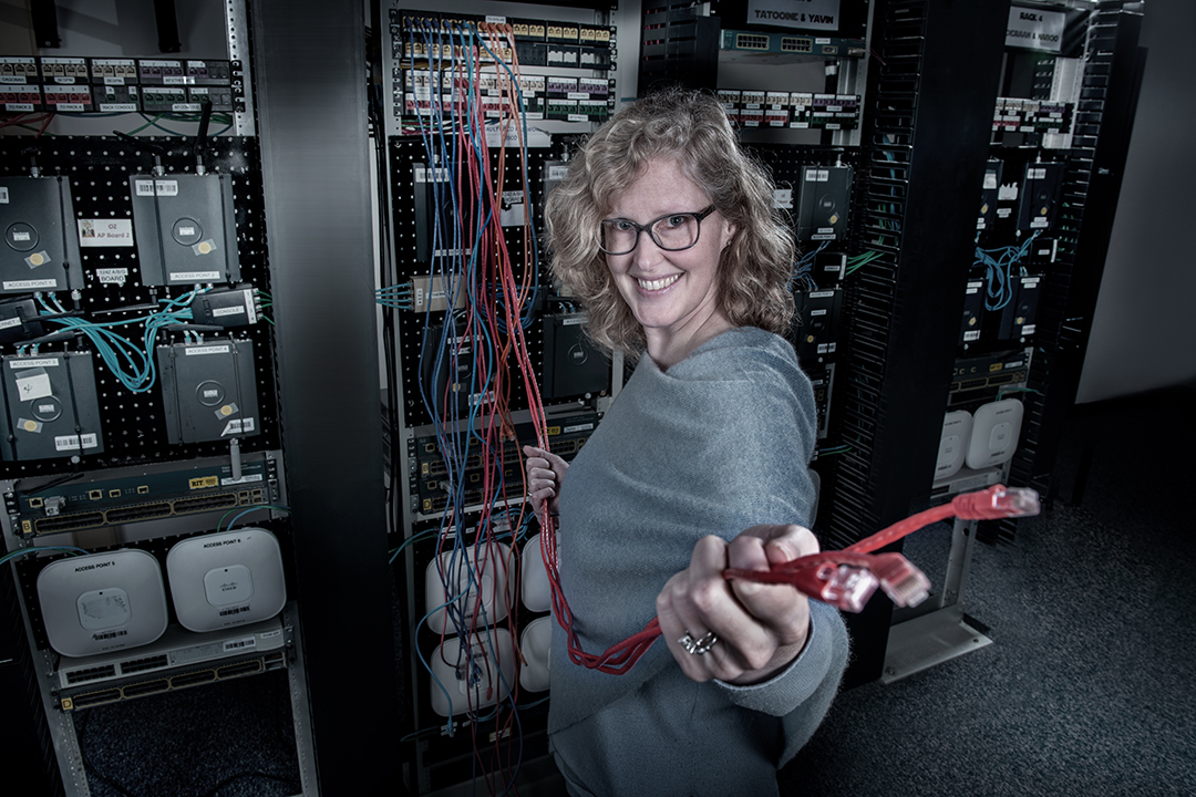 Person smiling and holding wires towards camera.