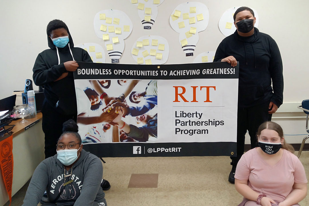 Four youth students holding an RIT LPP sign