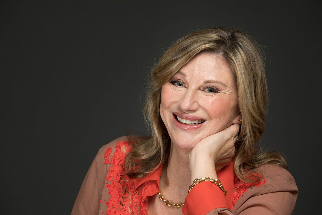 Portrait of Debra Meiburg with a dark background.