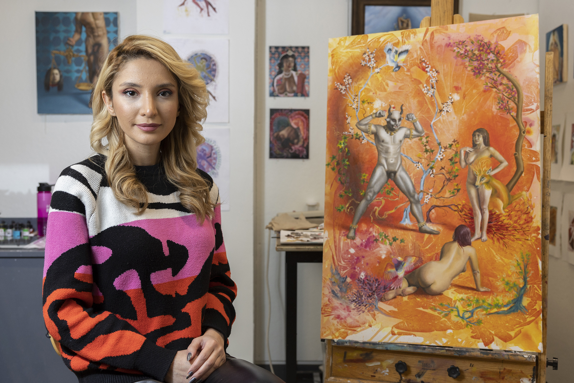 Nava Barenji sits next to one of her paintings.