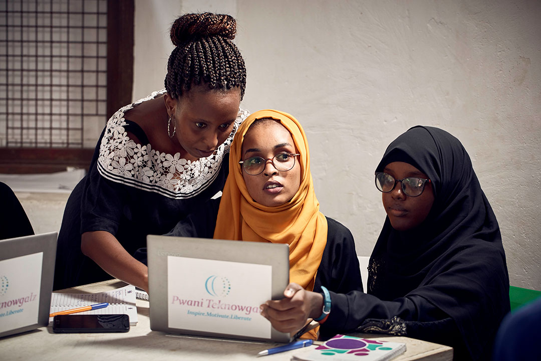 woman with two female students looking at a laptop in Kenya.