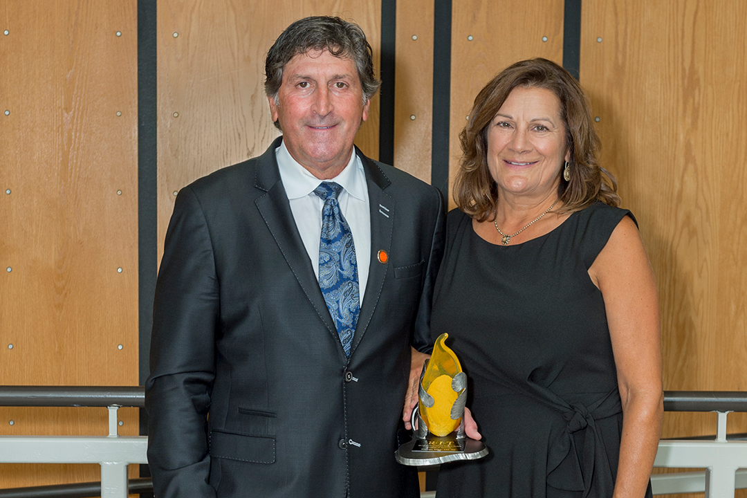 Photo of alumnus, male, left, and female, right and award statuette