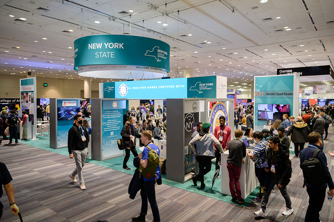 several booths under a New York State sign at the Game Developers Conference.
