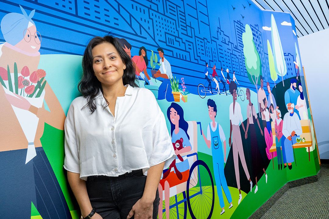 Maricela Marquez standing in front of a wall with a mural.