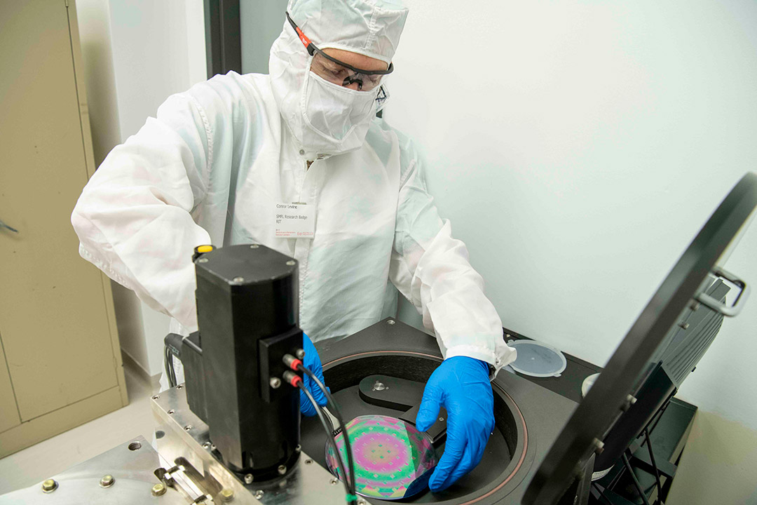 person wearing clean suit handling a semiconductor.