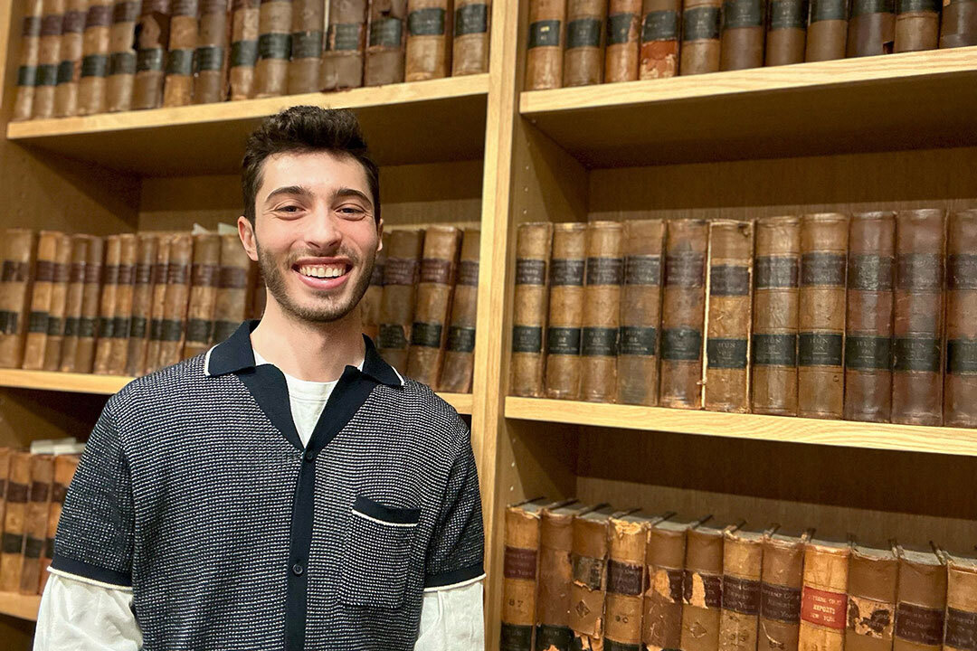 college student standing in front of a bookcase.