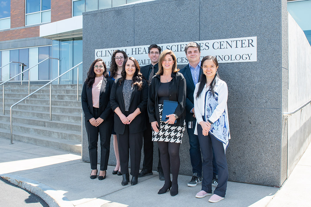 seven researchers posing for a photo outside of R I T's clinical health sciences center.